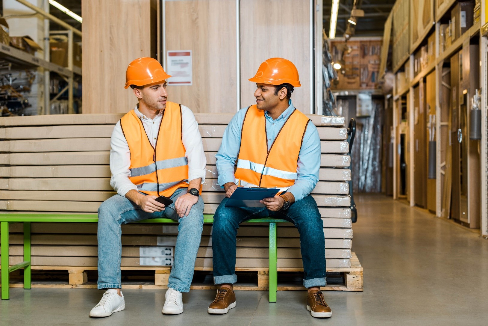 Two warehouse workers discuss health and safety practices