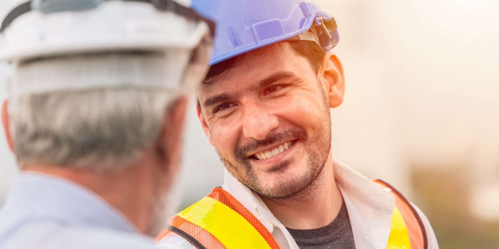 Worker in safety gear talks to his supervisor